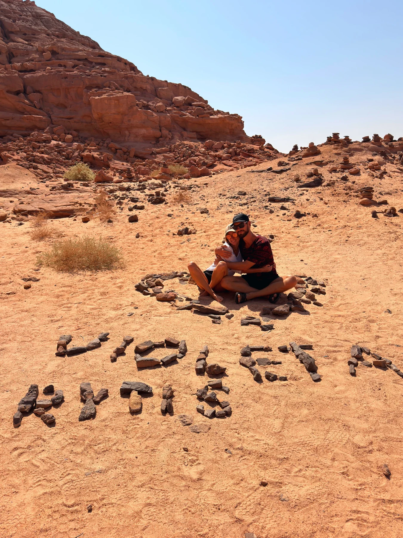 Rytis and Violeta sitting together in a desert circle of stones