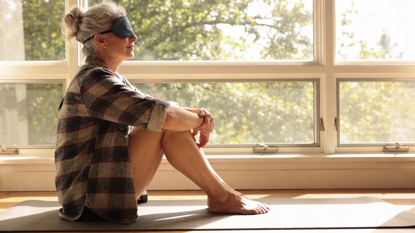 Woman in Feeling Session posture on a grounded mat, T-shirt over eyes, side angle, embodying a phase Woman in Feeling Session posture on a grounded mat, T-shirt over eyes, side angle, embodying a phase of the five-phase process for childhood trauma symptoms — symptoms of childhood trauma in adulthood