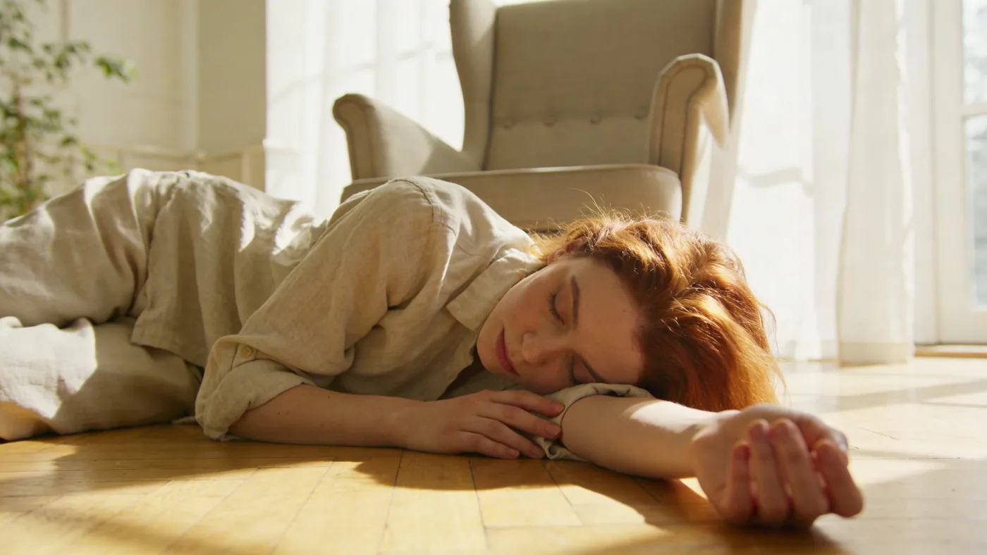 Woman lying still on wooden floor with eyes covered, inner child healing practice of deep rest and surrender