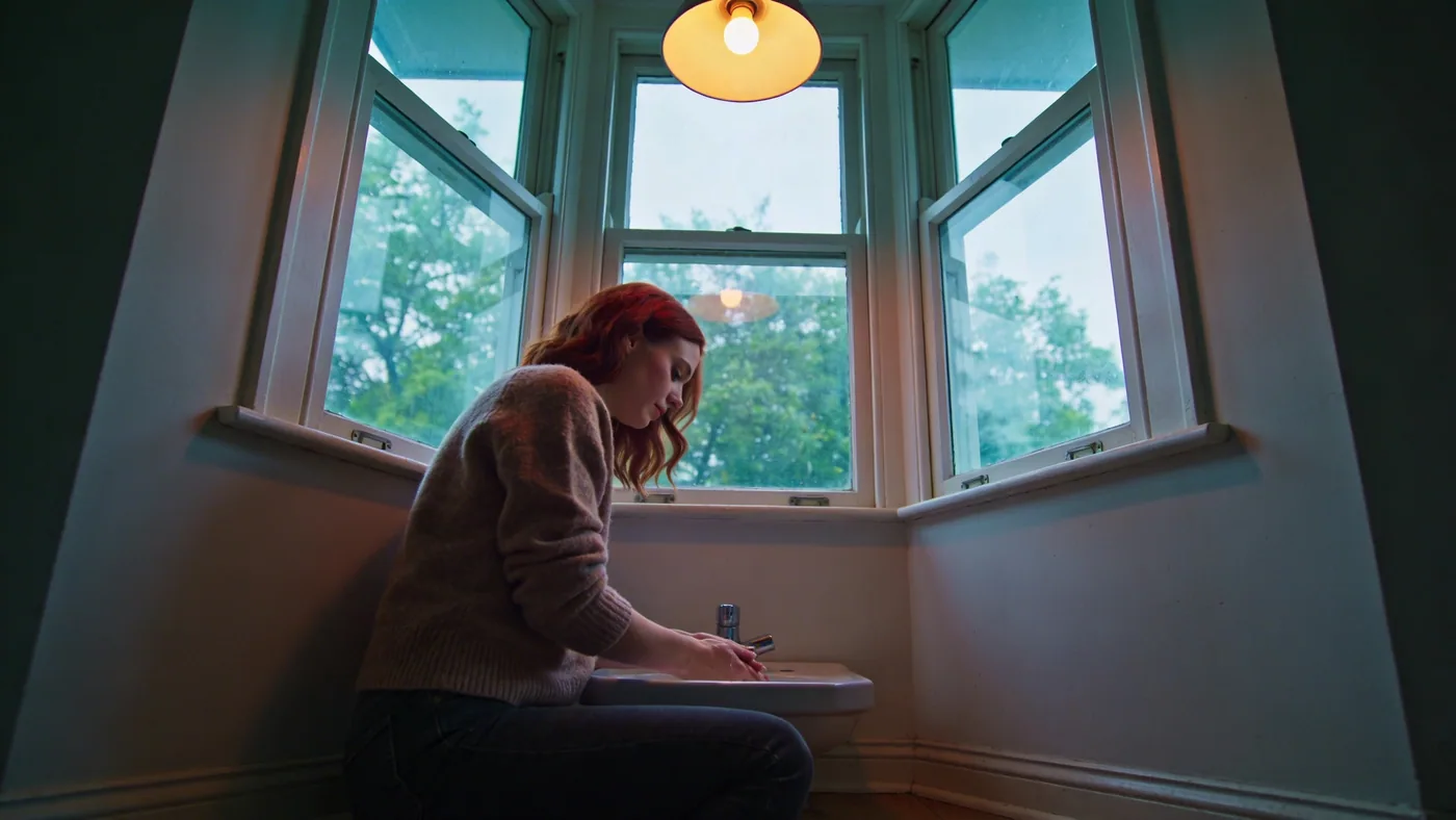 Woman washing hands at a simple bathroom sink in quiet reflected light, a moment of clarity after resentment passes — how to let go of resentment