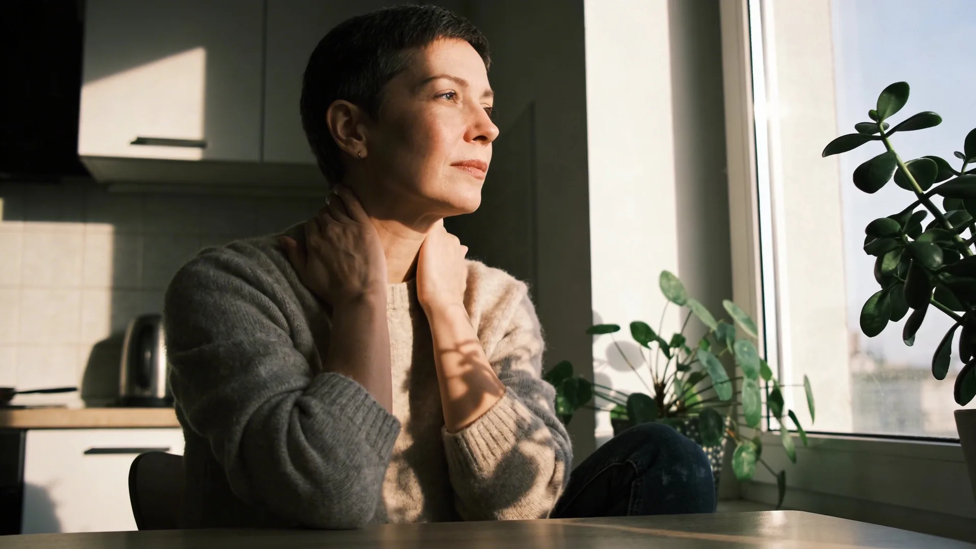 Man at desk touching his neck showing signs of adhd burnout with bright natural window light