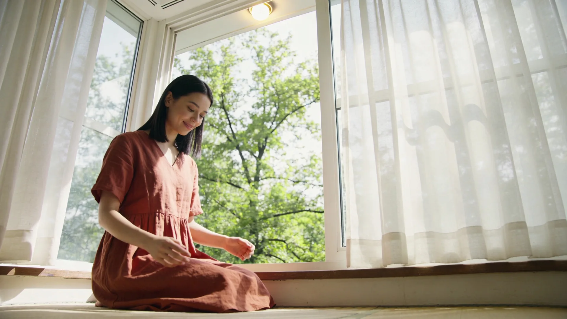 Person wrapped in blanket looking through rain-streaked window as light returns after adhd burnout