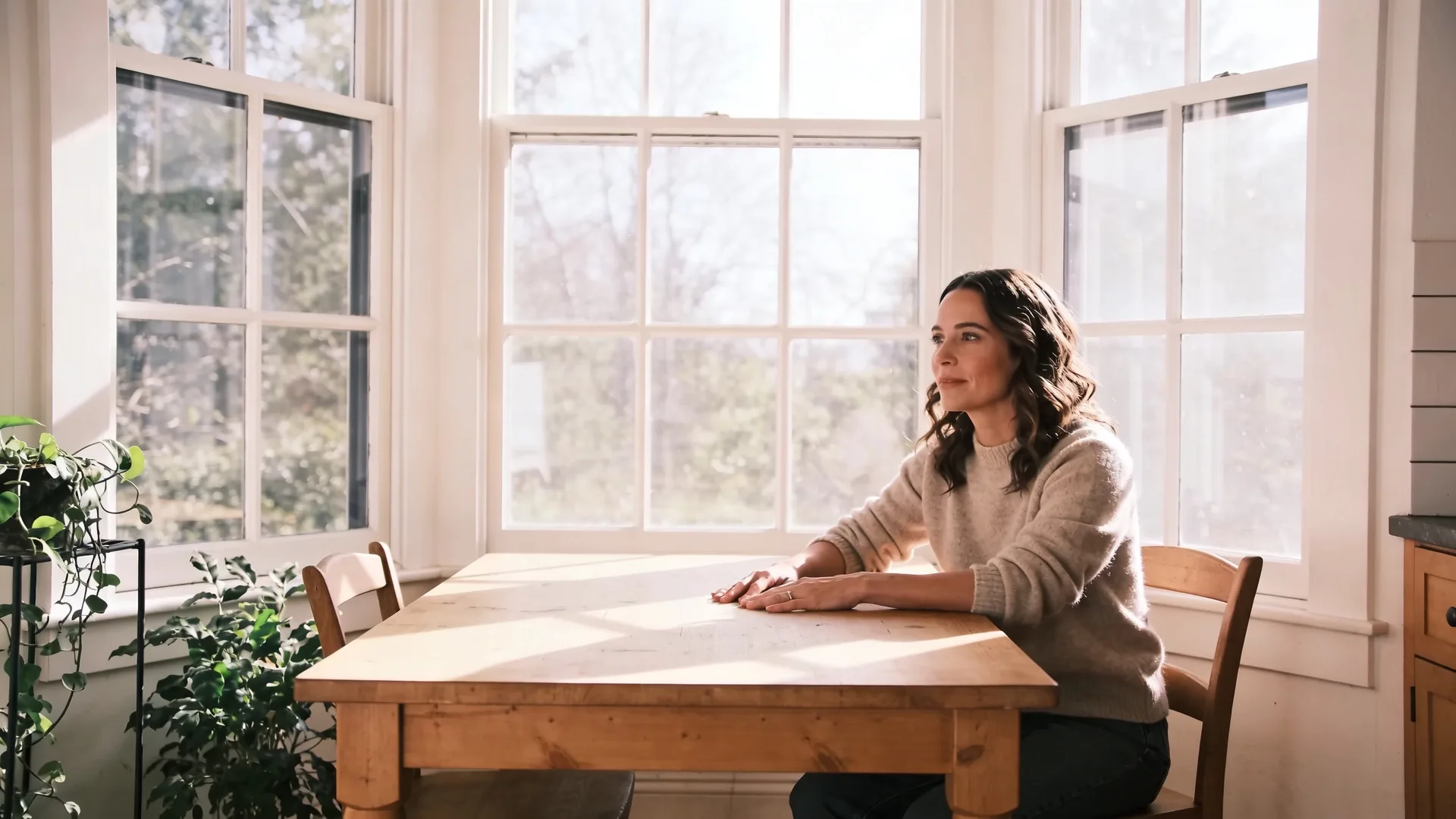 Hands resting gently on a handmade ceramic bowl on a wooden table — the body knowing before language arrives