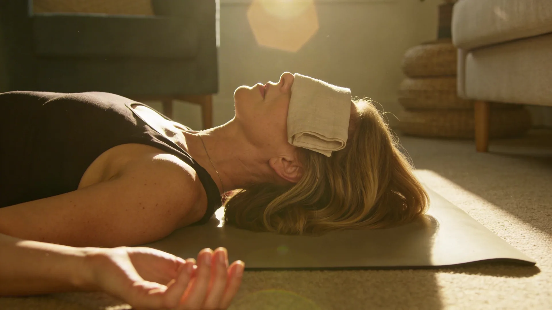 Woman lying on floor mat with palms down and eyes covered practicing a deep shadow work body session