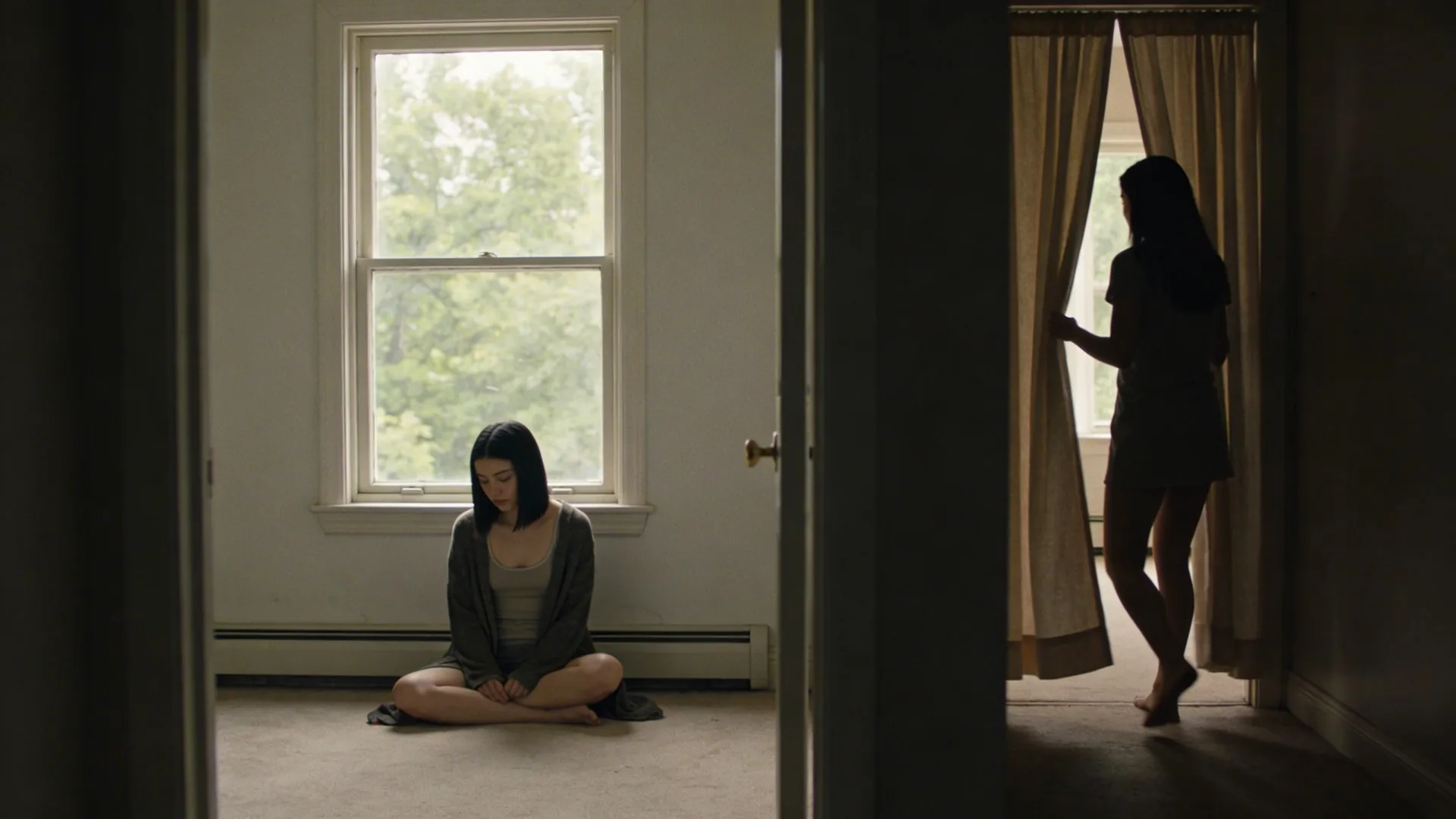Woman pulling back a curtain in a hallway, body moving toward light after recognizing what changed and softened