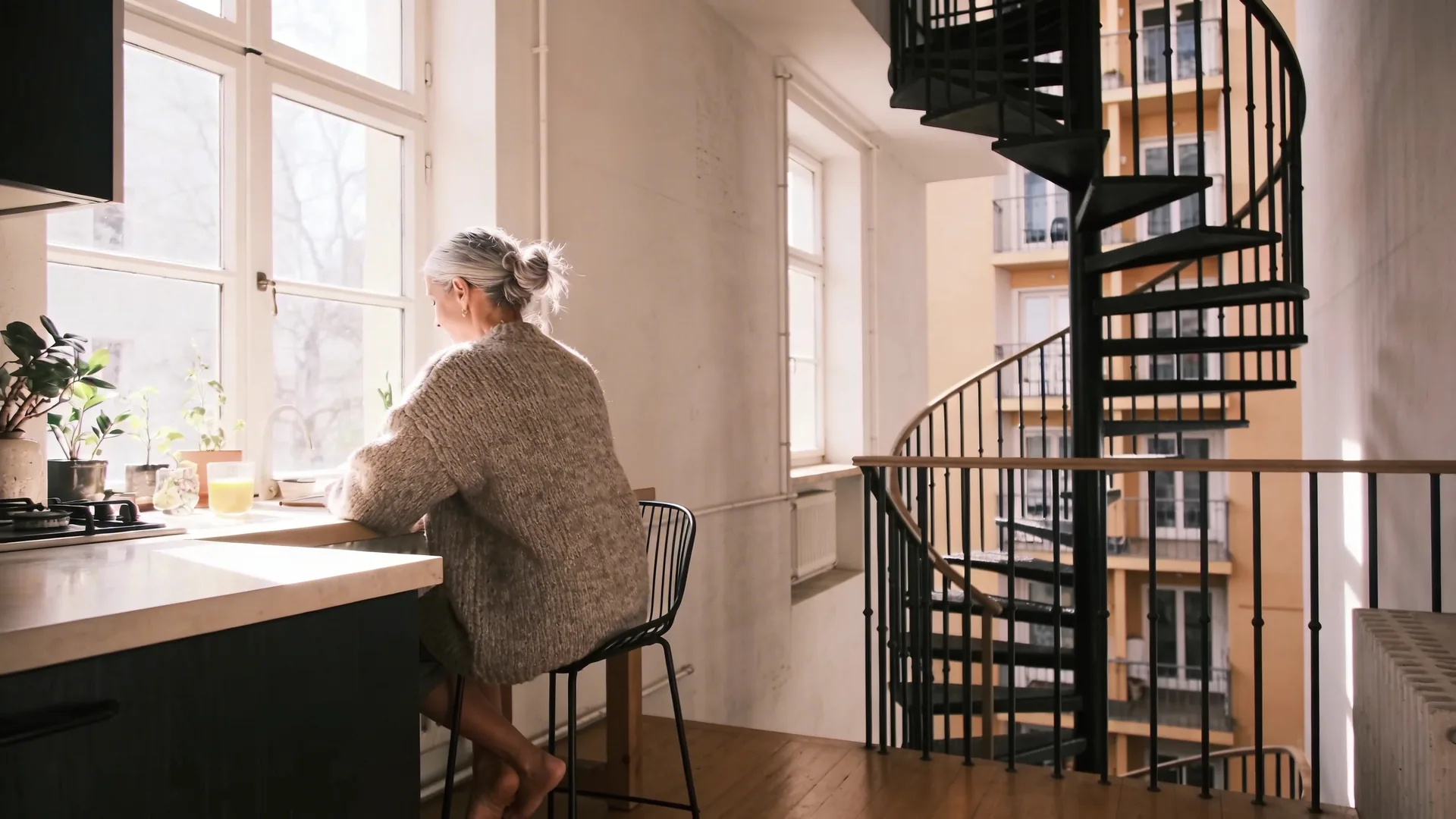Woman descending spiral staircase in apartment building visualizing the loop that keeps deep loneliness alive