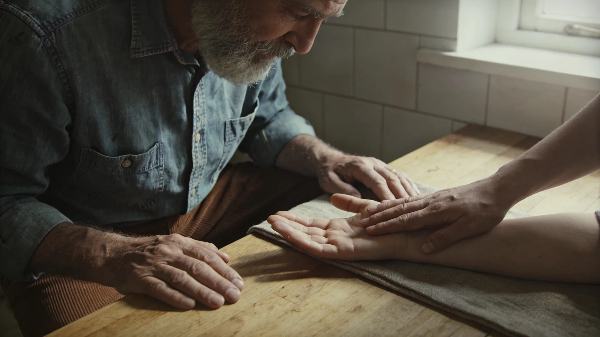 How to help someone having a panic attack — close-up of one hand resting palm-up beside another hand palm-down on a wooden table, helping someone with a pa