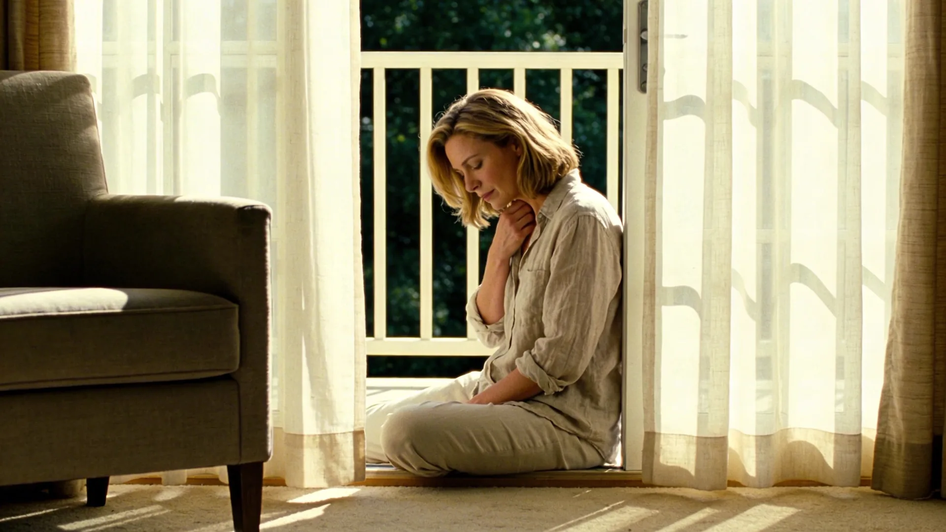 Woman at balcony threshold breathing slowly while her body settles into stillness