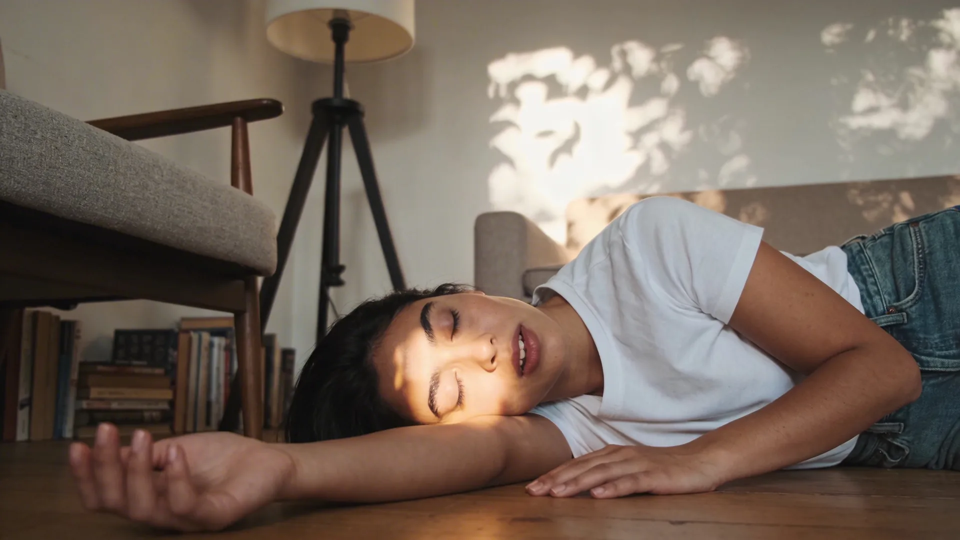 Woman lying on wooden floor in Feeling Session posture with palms down and eyes covered, exploring why emotions stay in the body