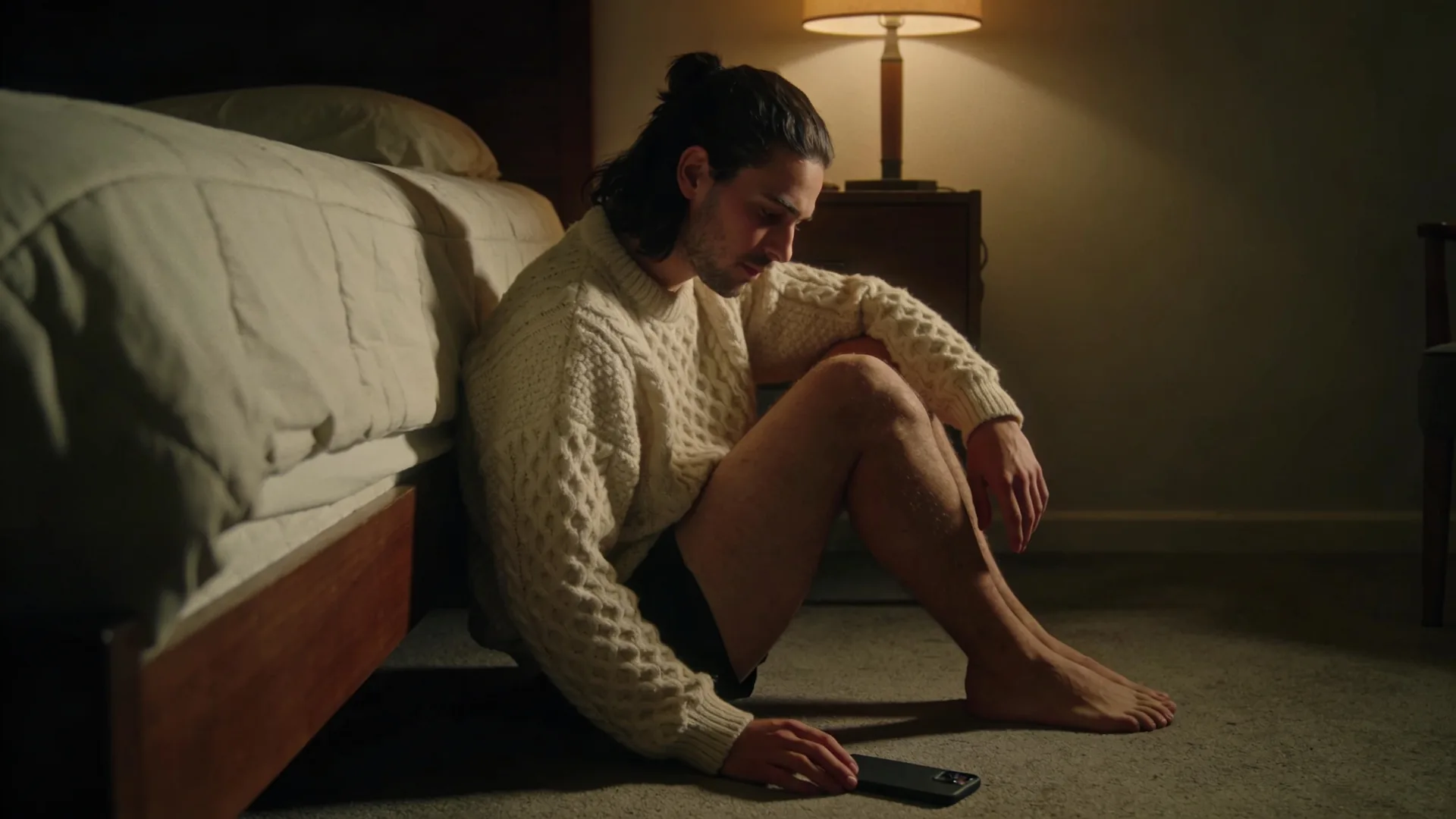 How to stop overthinking after being cheated on — seated on the bedroom floor against a bed, phone face-down beside the hand