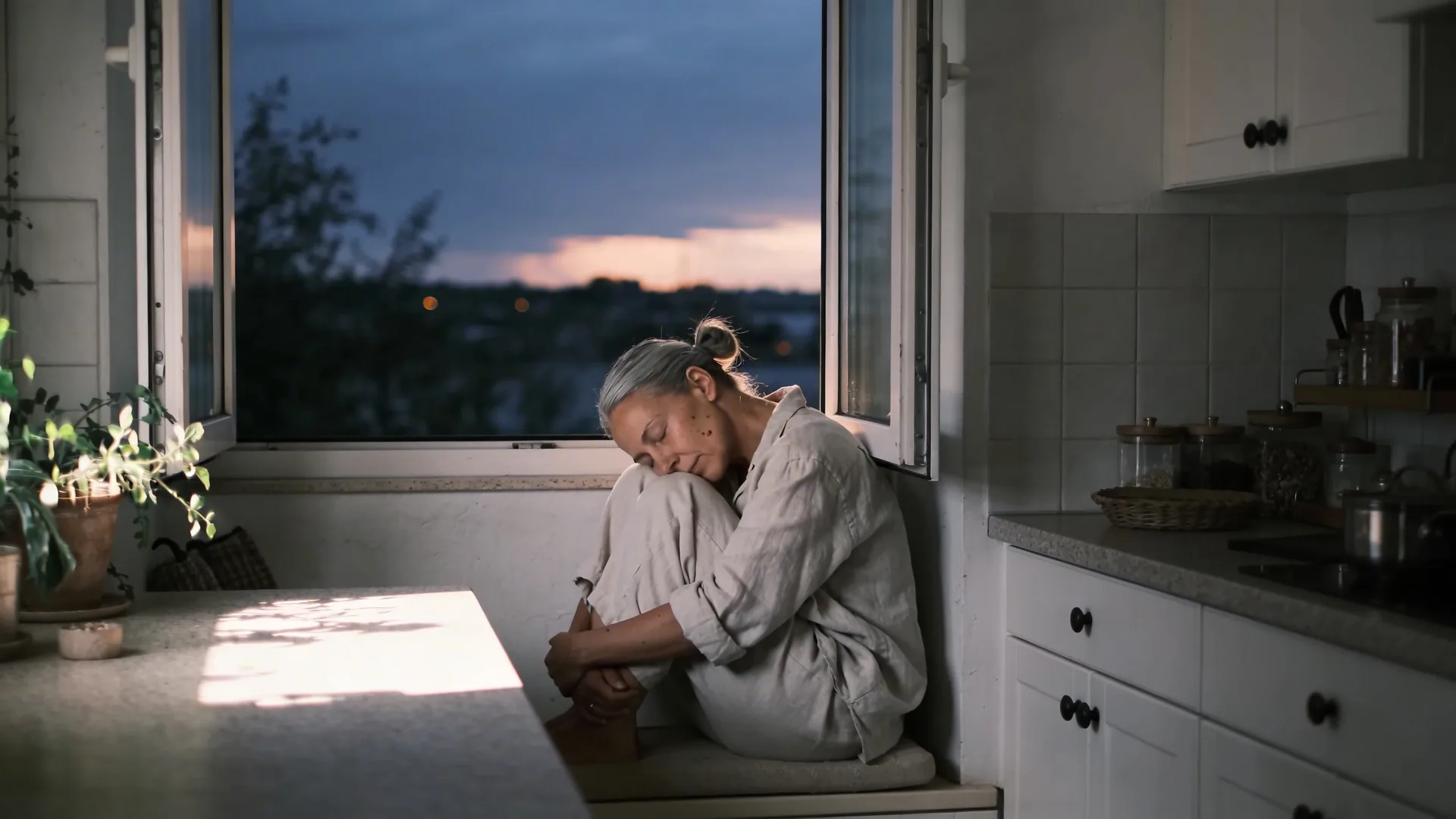 Woman curled in window seat with eyes closed, inner child posture in morning light