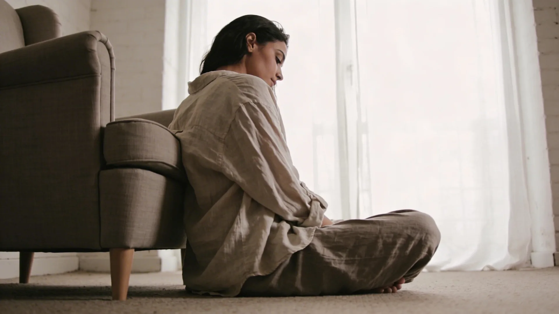 Woman looking away from her own reflection in a simple bathroom mirror exploring why self compassion meditation matters