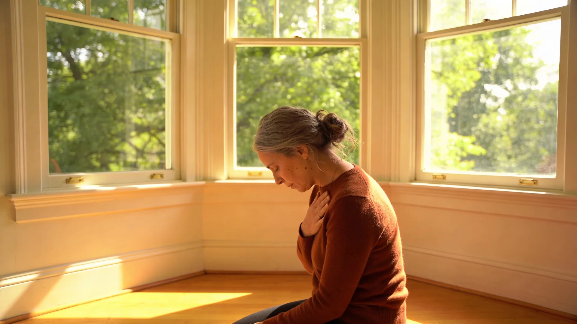 Man sitting on floor with hand on chest in natural light, start where shadow appears in the body