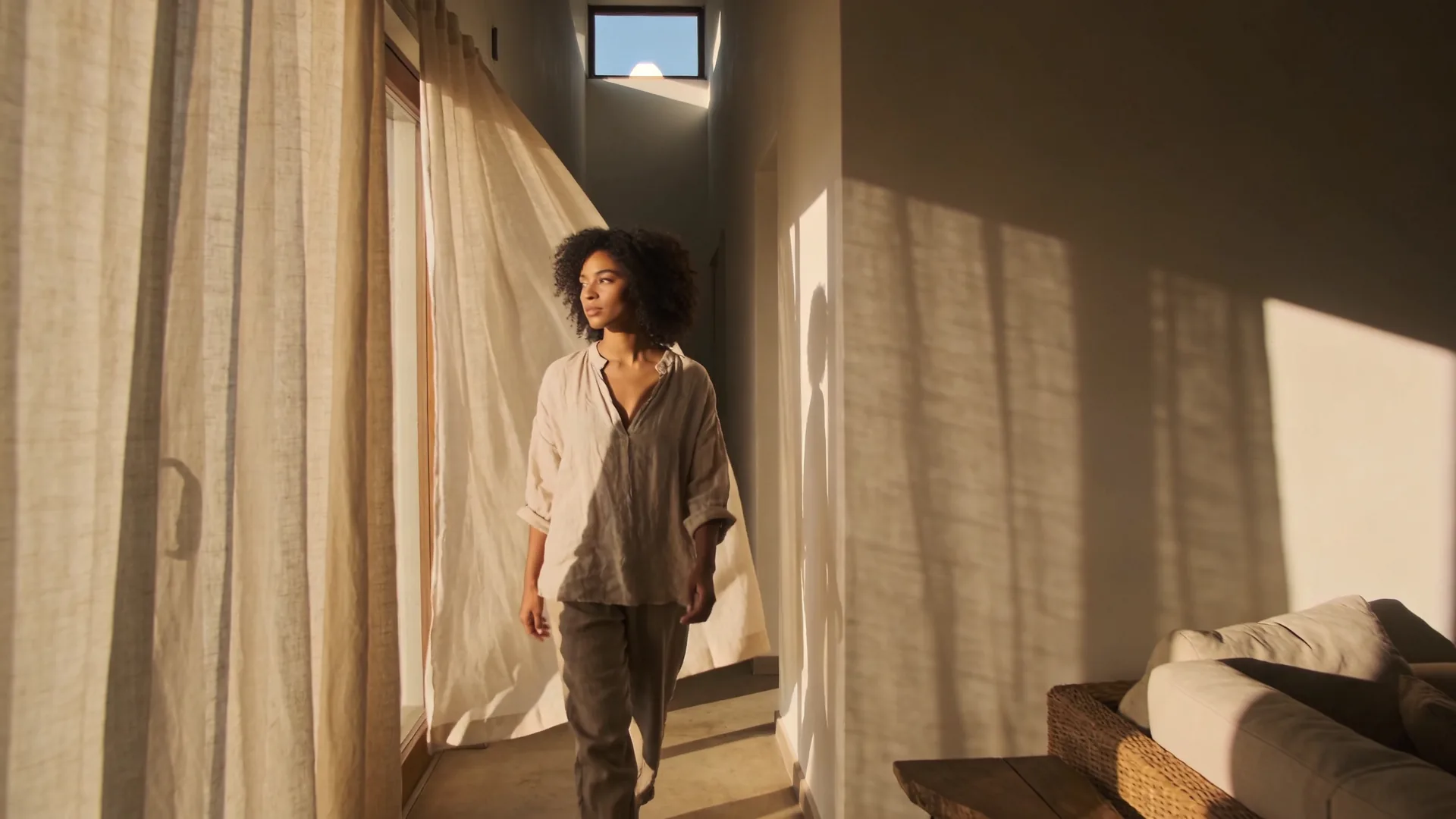 Woman walking barefoot down sunlit hallway, embodying somatic exercises to release trauma in hips in ordinary life