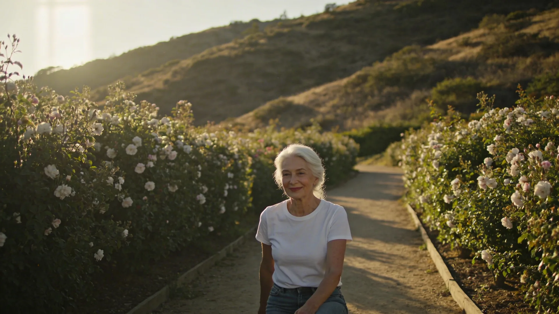 Woman walking a hillside path at golden hour with tense shoulders, beginning somatic exercises to release trauma