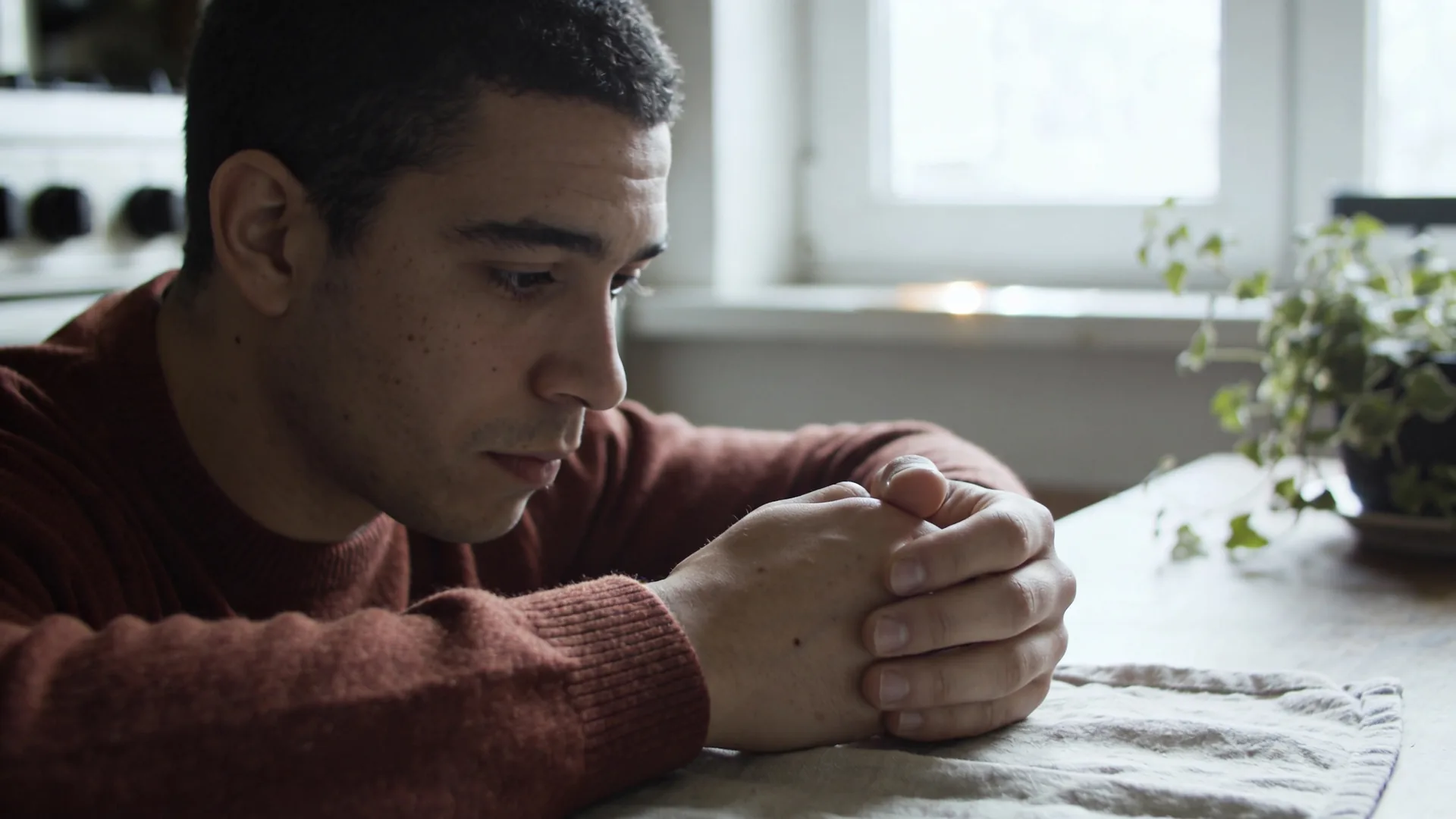 Close-up of tense curled hands on linen showing the body holding trauma even after the mind understands