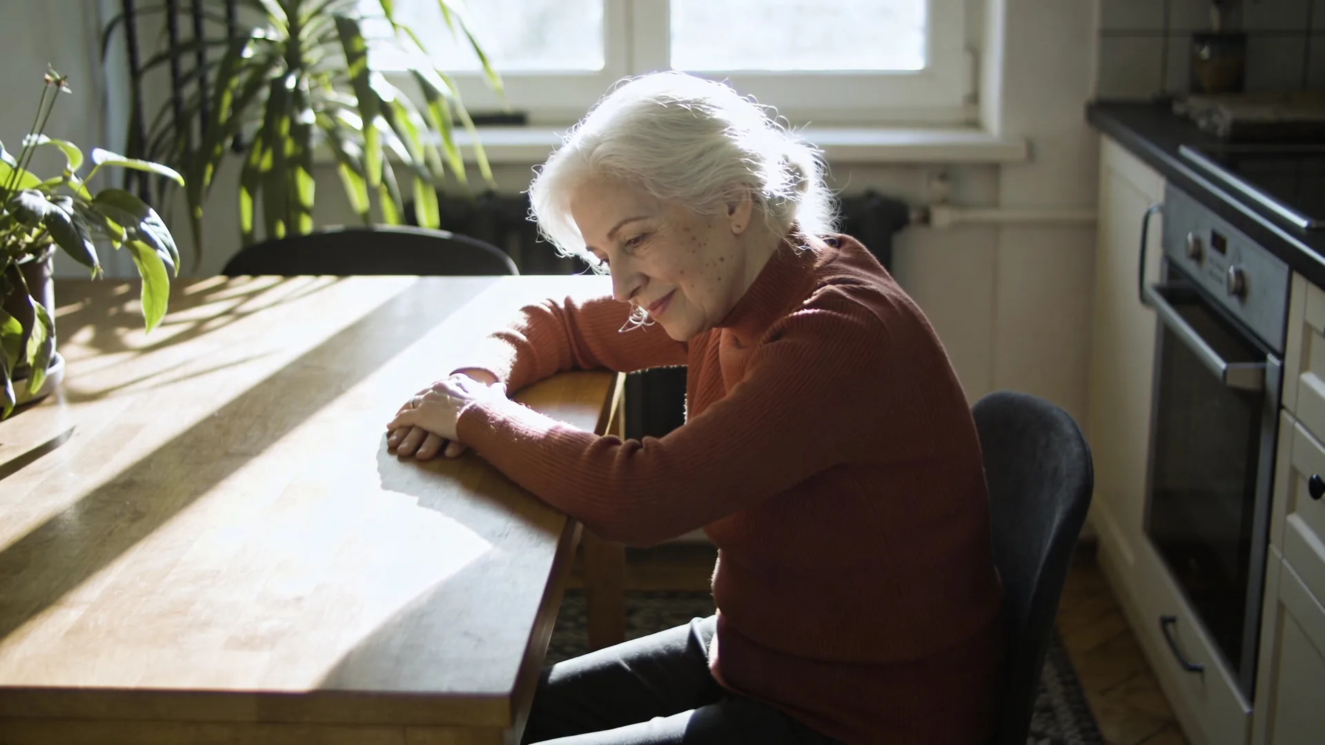 Hands resting on wooden table beside ceramic bowl in quiet domestic soul searching moment with soft side light