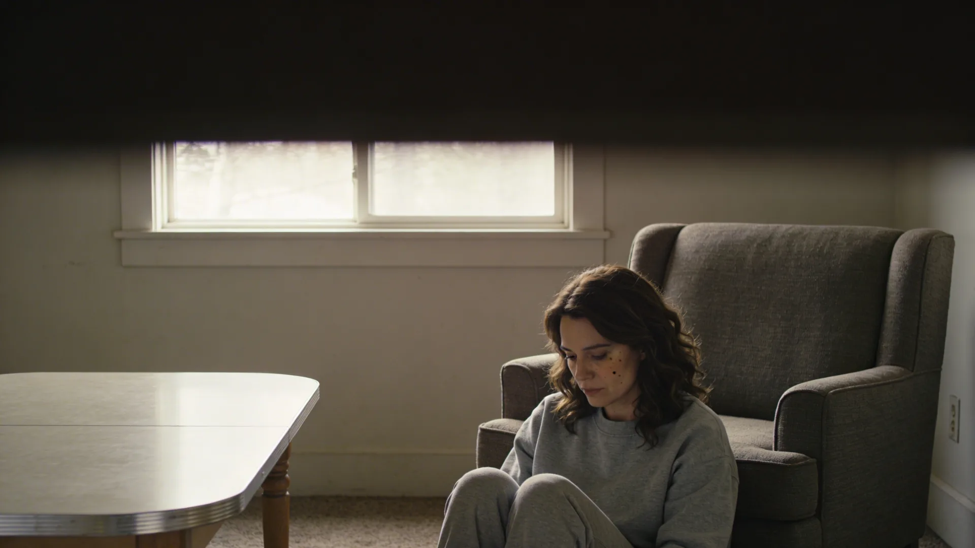 Hands resting on kitchen table with empty chair across it showing grief of losing friends
