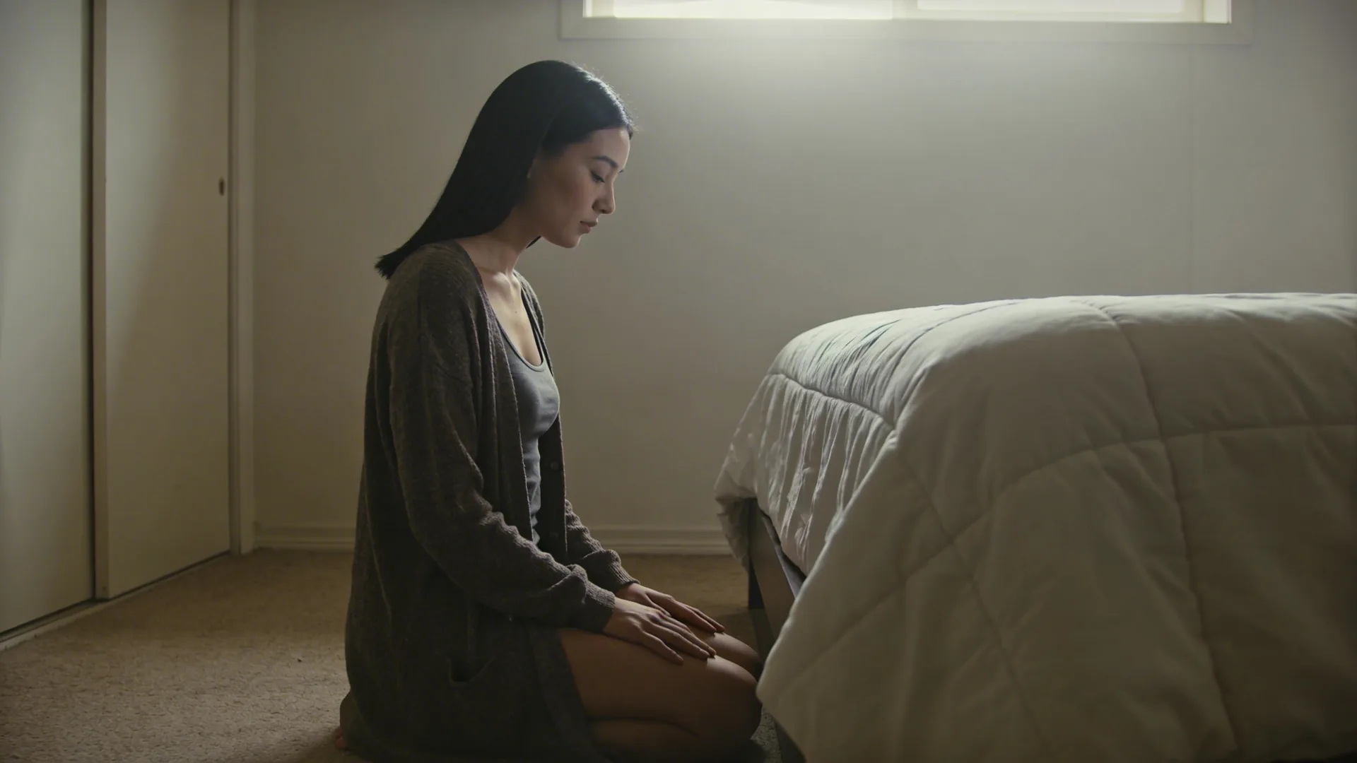 Woman touching her sternum in sunlit loft space experiencing spiritual awakening body sensations