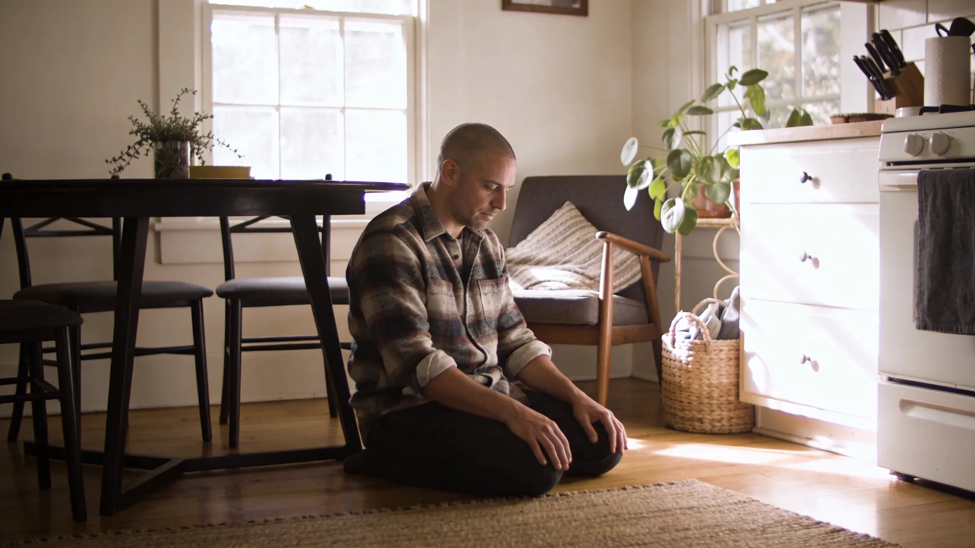 Woman with softened posture standing near open window in lived-in room after recognizing spiritual bypassing examples