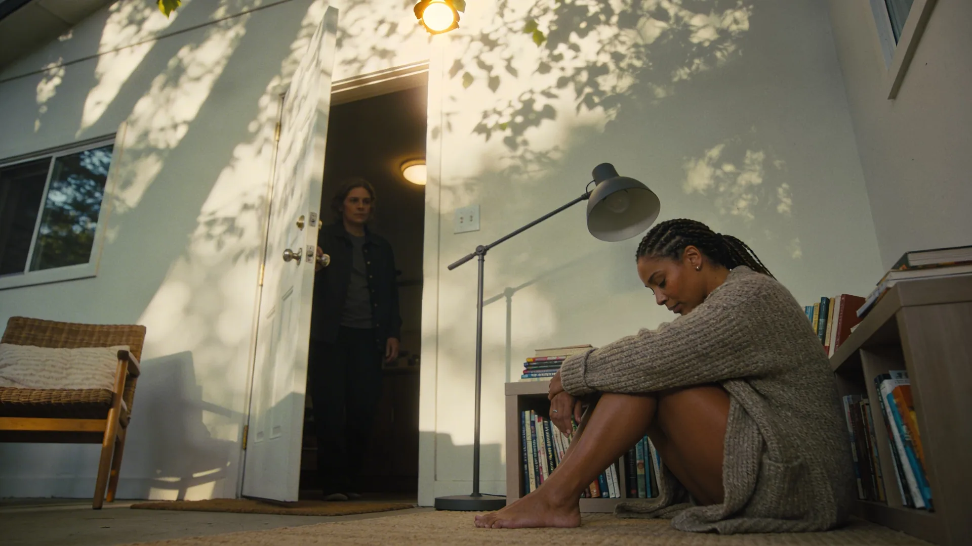 Person paused in a doorway between shadow and light during spiritual awakening collapse