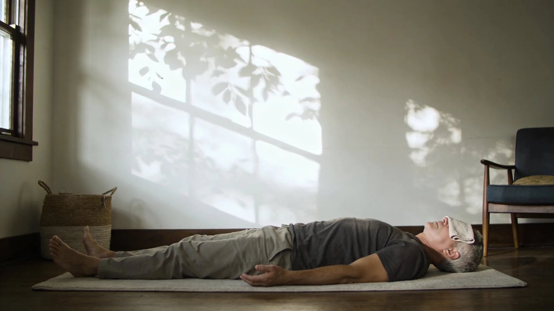 Woman lying on a mat with palms down and eyes covered practicing somatic yoga as a clear next step tonight