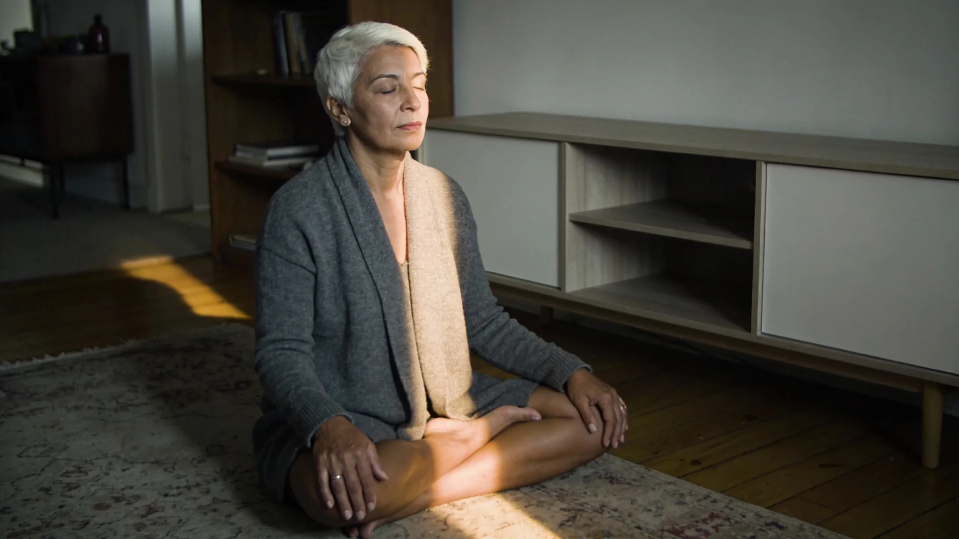 What is spiritual bypassing examples — seated cross-legged on the floor near a bookshelf, eyes closed, hands palm-down, what is spiritual bypassing