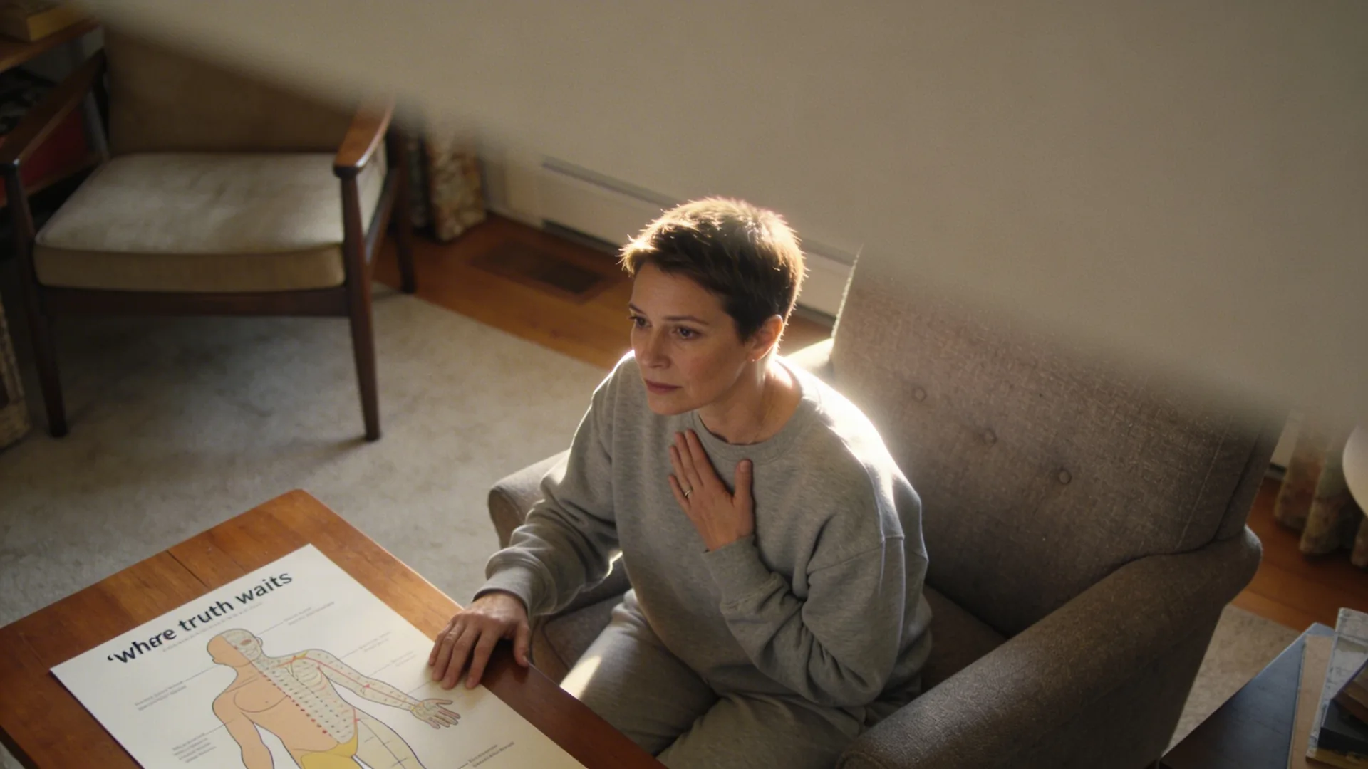 Woman's hand resting on her chest at a wooden table showing the body map where truth waits