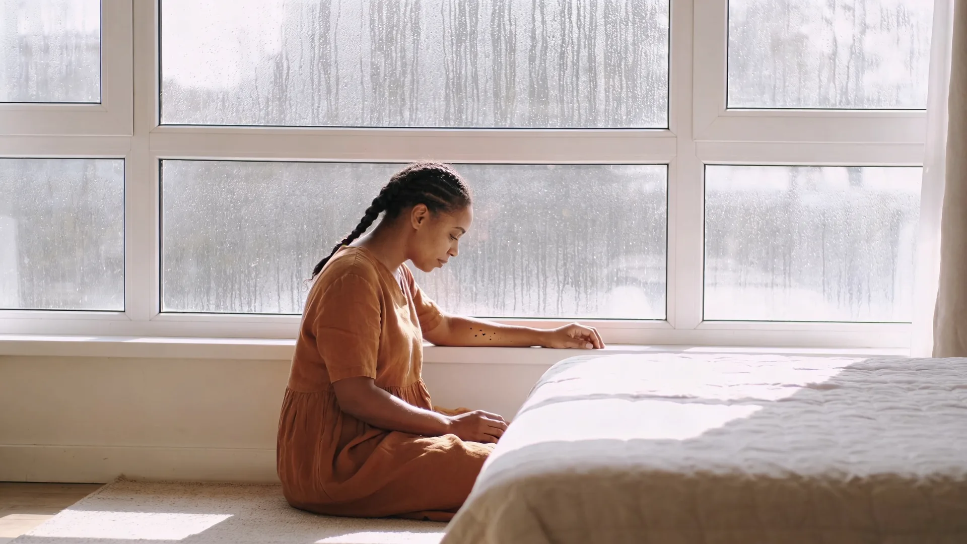 Ceramic mug on rainy windowsill with resting forearm showing the safety layer most spiritual content skips
